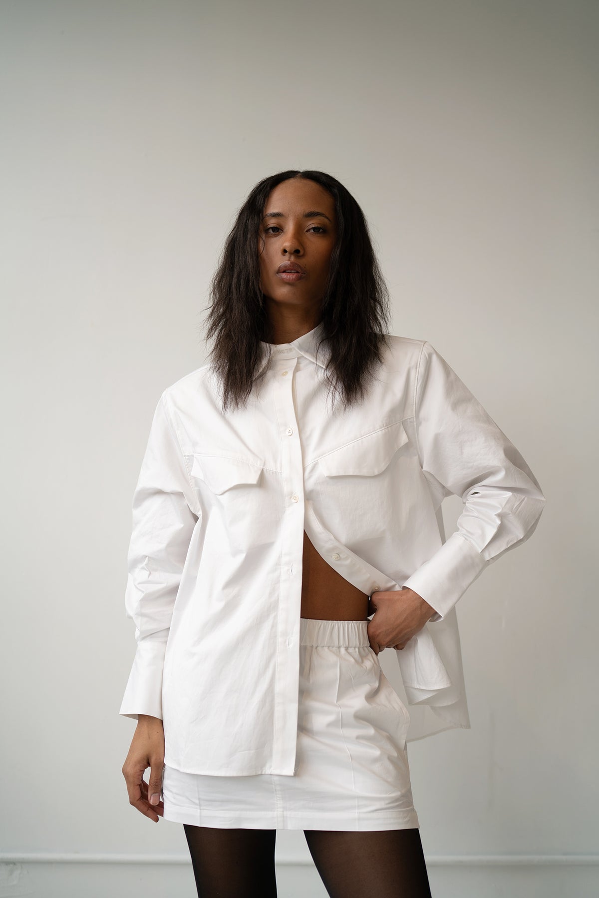 HCTR Mini Cotton Poplin Boxer Skirt in White — front view with white overshirt, model 5'9" wearing size S