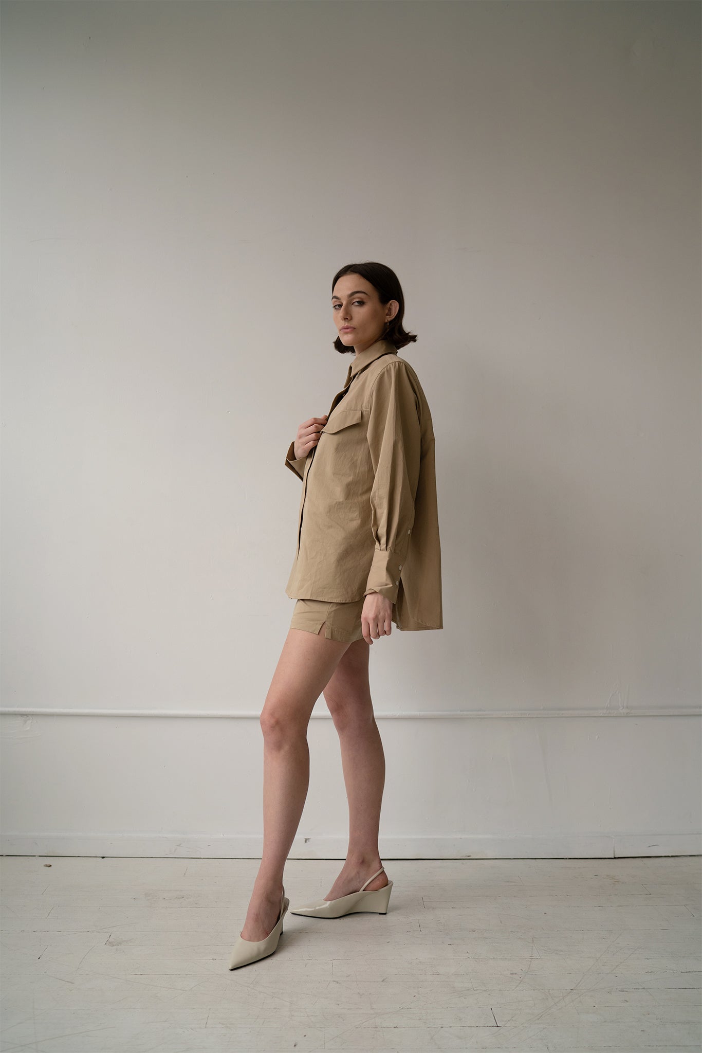 HCTR Oversized Cotton Poplin Button Down in Fawn styled with matching boxer skirt and white slingback heels, three-quarter view