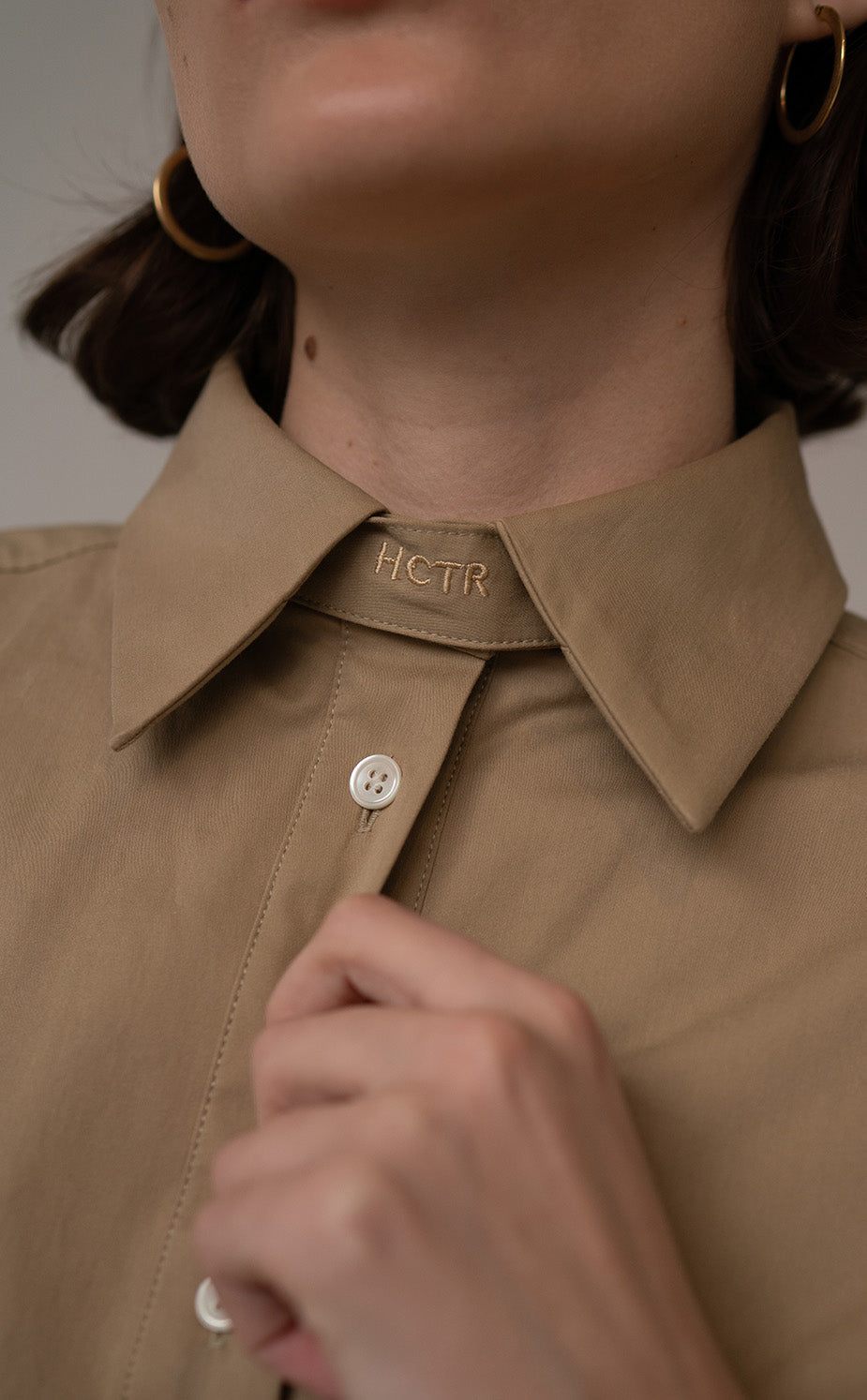 Close-up of HCTR reversible collar tab detail on the Oversized Cotton Poplin Button Down in Fawn
