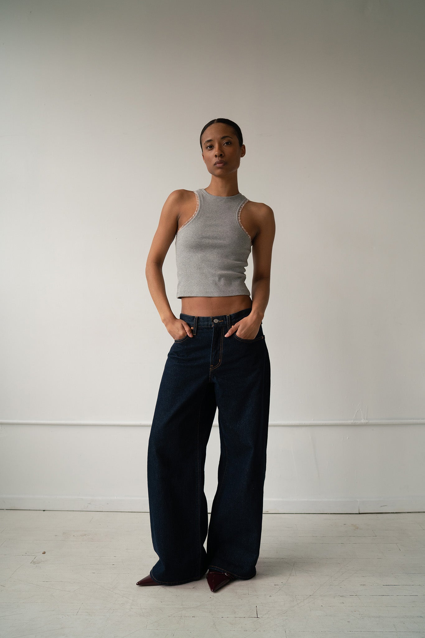 HCTR Dual-Neckline Reversible Ribbed Tank in Grey — full front view styled with dark wide-leg jeans, hands in pockets