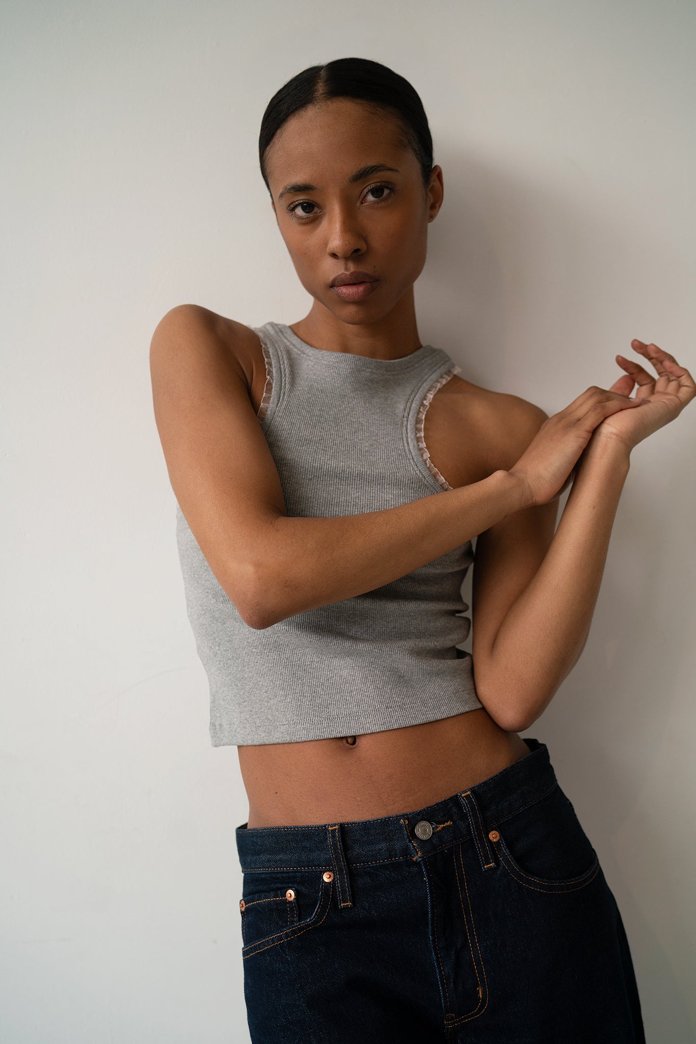 HCTR Dual-Neckline Reversible Ribbed Tank in Grey — fitted cropped silhouette with pearlescent armhole trim, arms raised