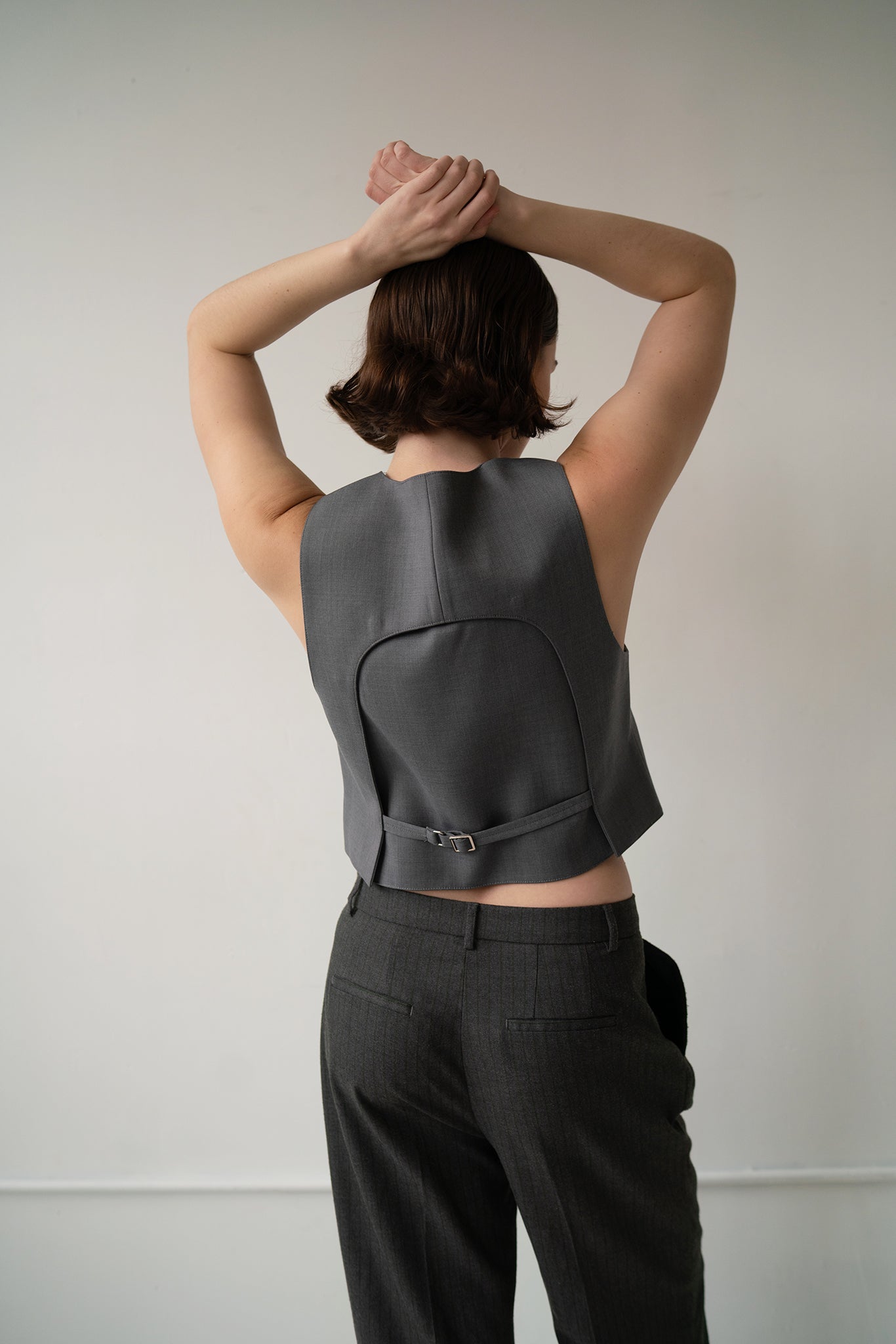 HCTR Modular 100% Wool Waistcoat in Grey — back view showing removable back panel with belt closure, arms raised